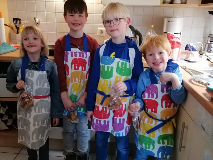 Vier Kinder mit Schürzen stehen vor einer Küchenzeile