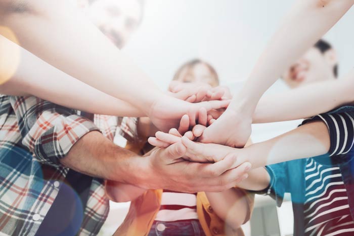 Eine Gruppe Erwachsene, die ihre Hände übereinander legen