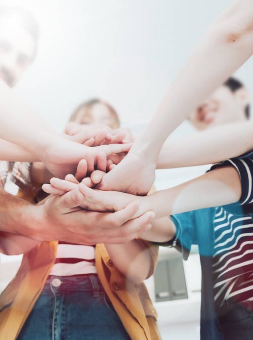Eine Gruppe Erwachsene legt ihre Hände übereinander