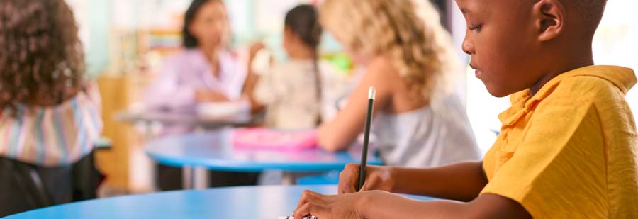 Ein schwarzer Junge sitzt an einem blauen Tisch und schreibt